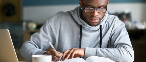 closeup-smart-millennial-african-student-wear-glas Closeup smart millennial african student wear glasses hold pen noting writing down information study use book preparing for university or college test exam, horizontal photo banner for website header