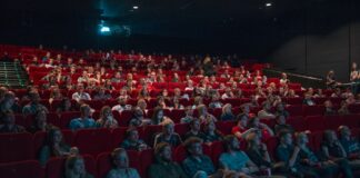 How can a student write a professional film review? person watching movie