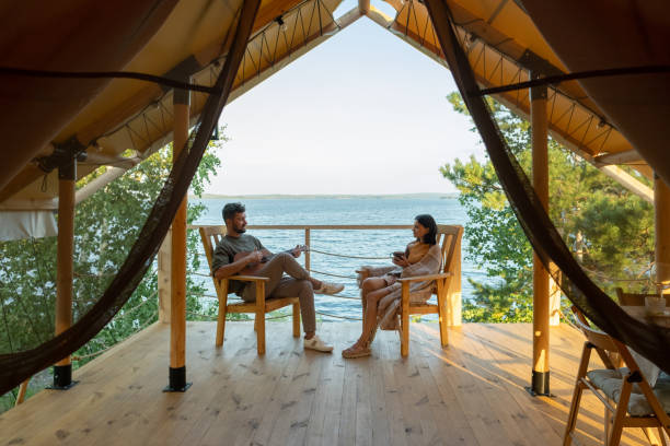 Happy amorous couple relaxing in wooden armchairs on patio by glamping house https://lh4.googleusercontent.com/4F1EkZSQJXVRJCV_iJJVGhCOOoVYI3Kh7rkiH9knP-OswaJa7DE8w1U3YUf3aKgxe3nRIQWFCREsA6PEbz2IBjbnG2OzSnq4GOB8fifwHYYTf9dx7nPMr3WOq9oag25OHeHV6xVn