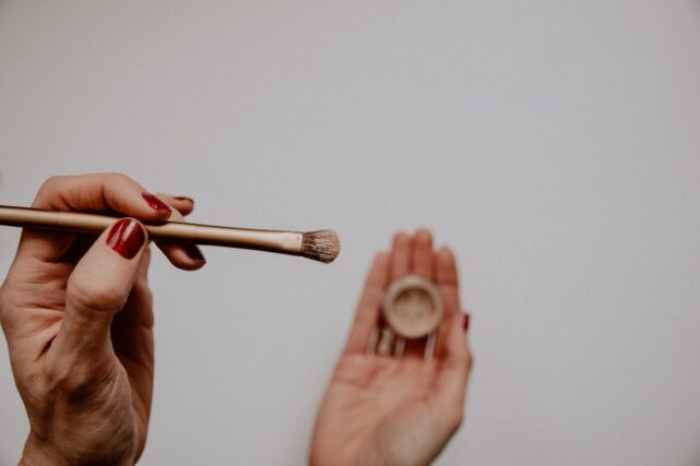 Photo by Kelly Sikkema person holding brown and white makeup brush