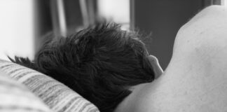 grayscale photo of woman lying on bed