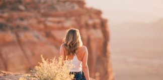 woman sitting on cliff during daytime
