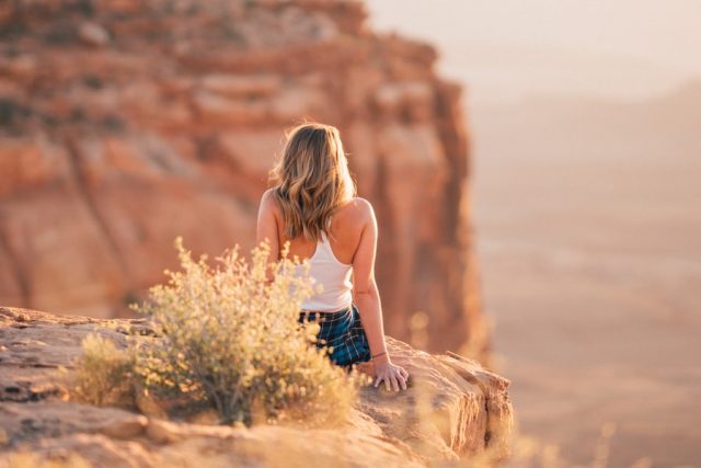 Photo by colton strickland woman sitting on cliff during daytime