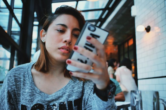 Photo by Rendy Novantino woman in gray and black sweater holding white and black iphone case