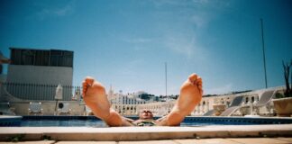 person lying on white concrete bench during daytime