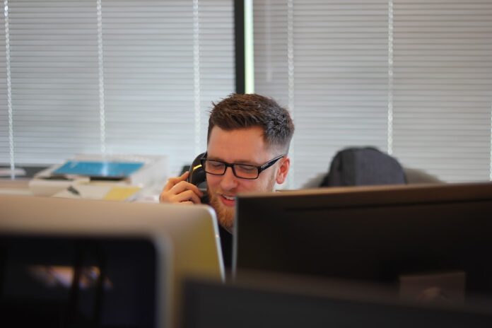 Photo by Berkeley Communications man using IP phone inside room