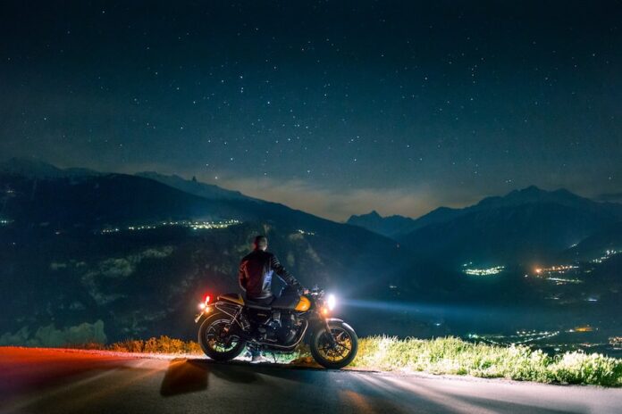 Photo by Duncan Adler man siting on motorcycle at night