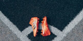 pair of orange adidas cleats on gray surface