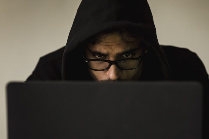 Photo by Sora Shimazaki Serious young male programmer wearing black hoodie browsing netbook and hacking software in studio