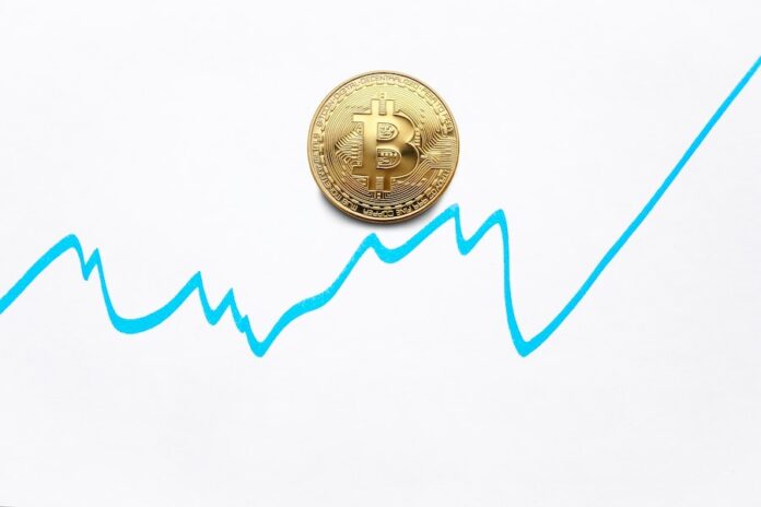 Photo by Ivan Babydov Gold bitcoin cryptocurrency coin and blue graph of changes of value on white background