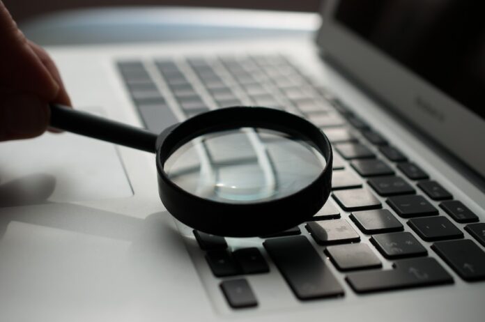 Photo by Agence Olloweb magnifying glass near gray laptop computer