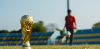selective focus photography of gold-colored trophy on grass field during daytime