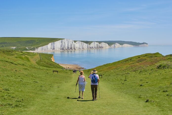 Photo by Marc Najera 2 men standing on green grass field near body of water during daytime