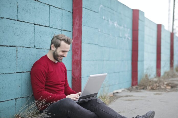 Photo by Andrea Piacquadio Man Leaning Against Wall Using Laptop
