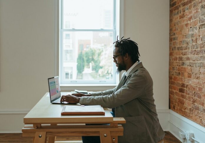Photo by Windows a person sitting at a desk with a laptop and papers