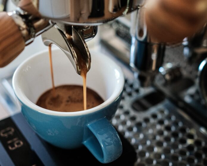 Photo by Andreas Behr blue ceramic mug on silver espresso machine
