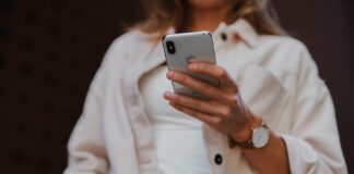 woman in white coat holding silver iphone 6
