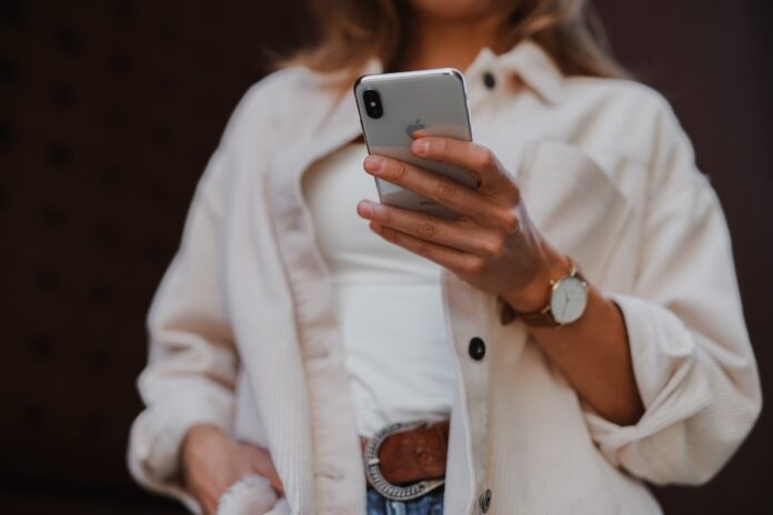Photo by Jenny Ueberberg woman in white coat holding silver iphone 6