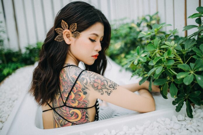 Photo by Anthony Tran women's orange and black floral back tattoo