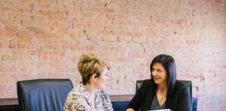 two women sitting on leather chairs in front of table