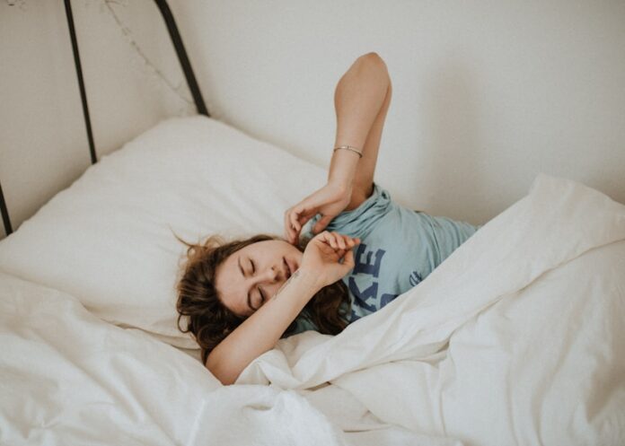 Photo by Kinga Howard woman covered in white blanket sleeping on white bed comforter