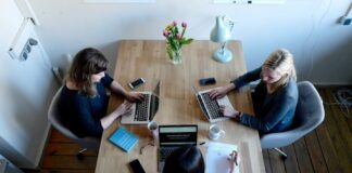 three women sitting around table using laptops