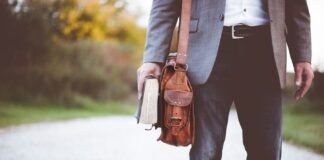 man holding book on road during daytime