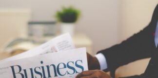person wearing suit reading business newspaper