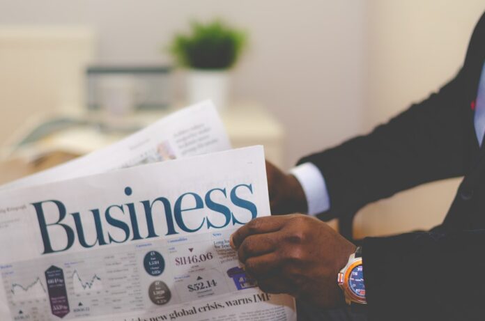 Photo by Adeolu Eletu person wearing suit reading business newspaper