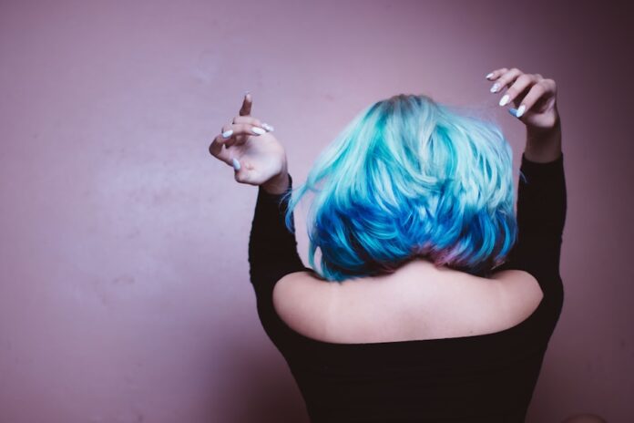Photo by Luis Quintero woman facing backward with blue hair