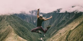 woman jumping on green mountains