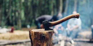 axe on tree log next to people sitting next to bonfire