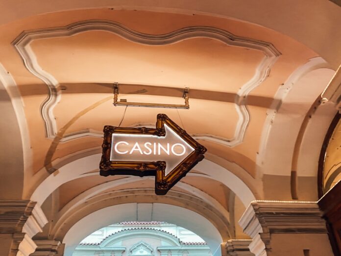 Photo by Jan Antonin Kolar a casino sign hanging from the ceiling of a building