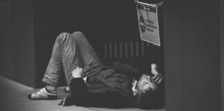 man lying on floor in grayscale photography