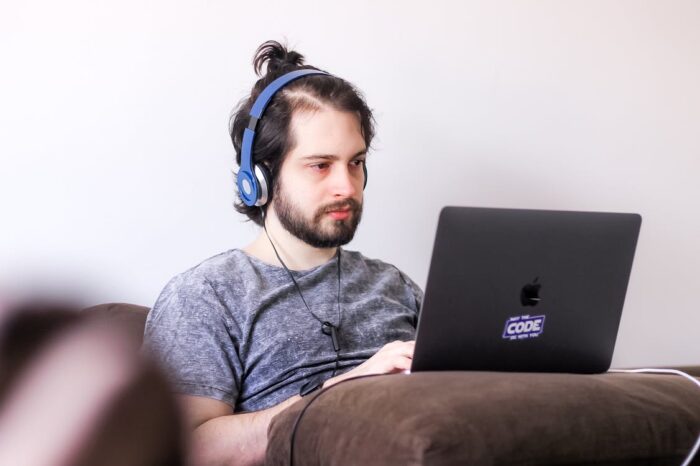Free Young Man Sitting on a Couch and Using and Laptop Stock Photo