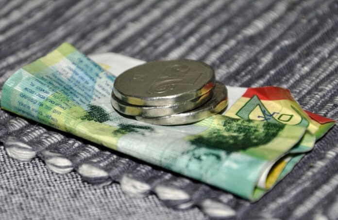 Photo by shraga kopstein a silver ring on a stack of money