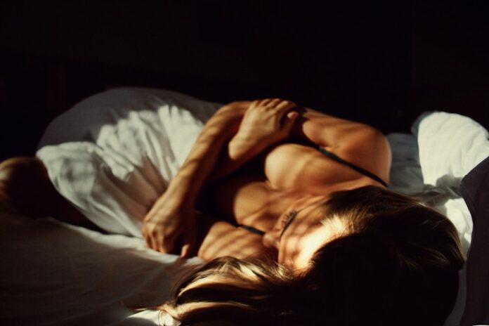 Photo by Daria Litvinova a woman laying on top of a bed next to a man