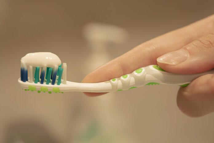 Photo by Roman Marchenko a person is holding a toothbrush with toothpaste on it