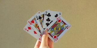 a person holding four playing cards in their hand