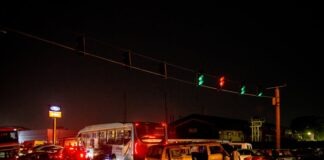 A crowded urban nighttime scene featuring a traffic accident at a busy intersection.