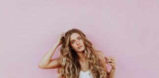 woman standing next to pink wall while scratching her head