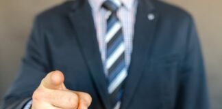 5 Key Errors to Avoid as You Start Your First Business A businessman in a dark suit points forward, emphasizing focus and professionalism.