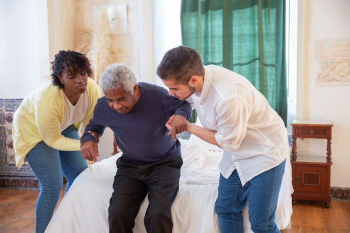 Photo by Kampus Production An elderly man receiving assistance from caregivers in a cozy home environment.