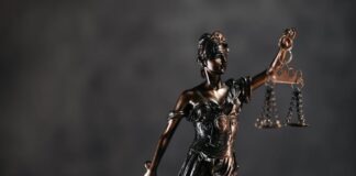 Detailed bronze Lady Justice statue with scales and sword against a dark background, symbolizing law and justice.