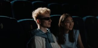 A couple watches a movie in a dark cinema, creating an intimate atmosphere.