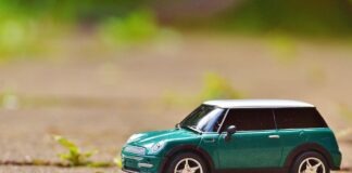 Green toy Mini Cooper car on pavement featuring a shallow depth of field outdoors.