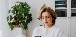 Woman with short hair using smartphone in cozy home setting.