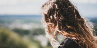 woman with long curly blonde hair using smartphone