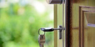 Key inserted in door lock against a blurred green background, symbolizing security and real estate.