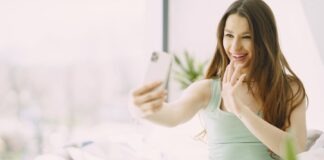Woman sitting on sofa making a video call, enjoying a bright day at home.